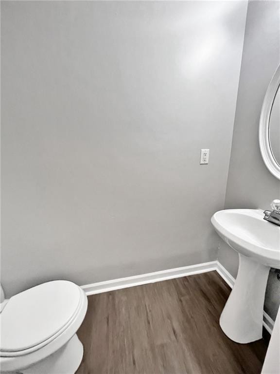 Half bathroom with baseboards, wood finished floor