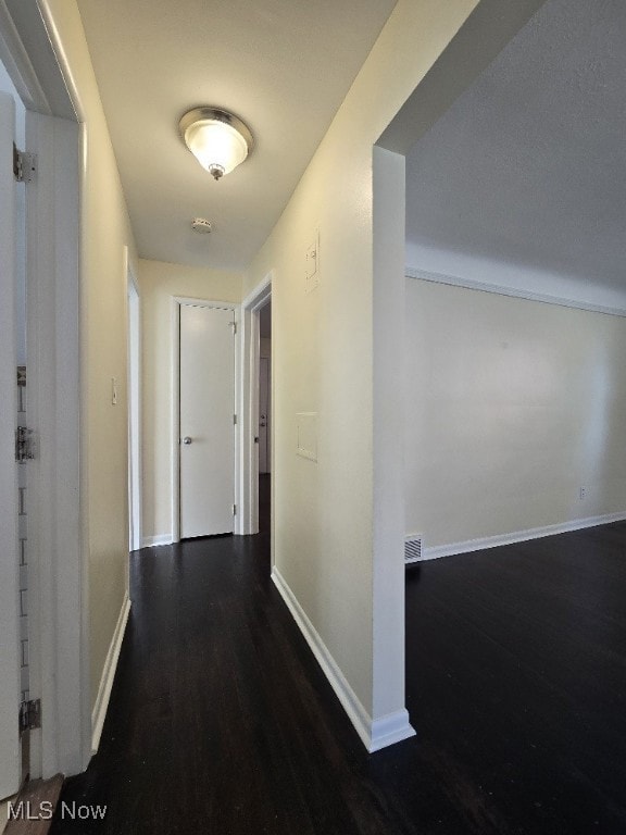 Hallway with dark wood-style flooring and baseboards