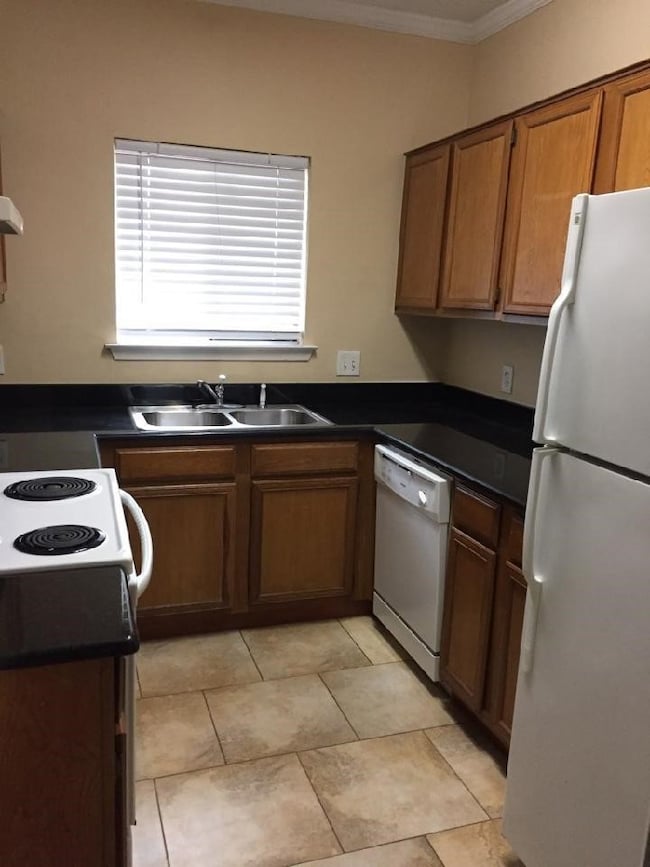 Kitchen featuring granite countertops, white appliances and ornamental crown molding