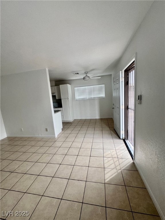 Unfurnished living room with plenty of natural light, light tile patterned floors, ceiling fan, and a textured wall
