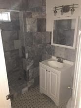 Full bath featuring vanity, a shower stall, and tile walls