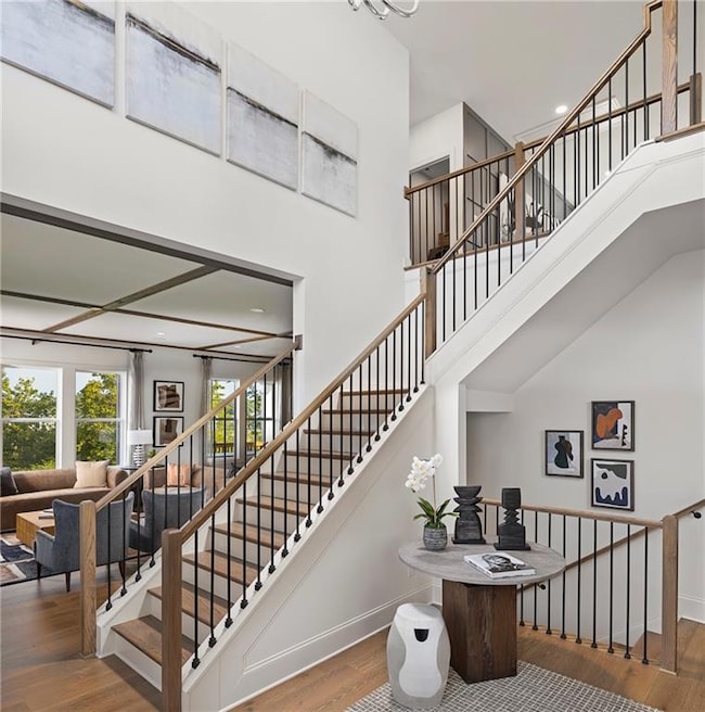 2 story foyer featuring recessed lighting, chandelier, wood finished floors and open stairs to basement. Photo is representative of the Acworth Model Home. Designer features will vary.