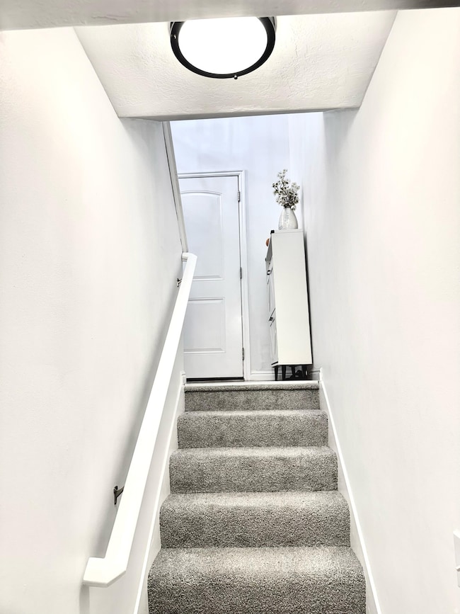 Stairs with a textured ceiling and carpet flooring
