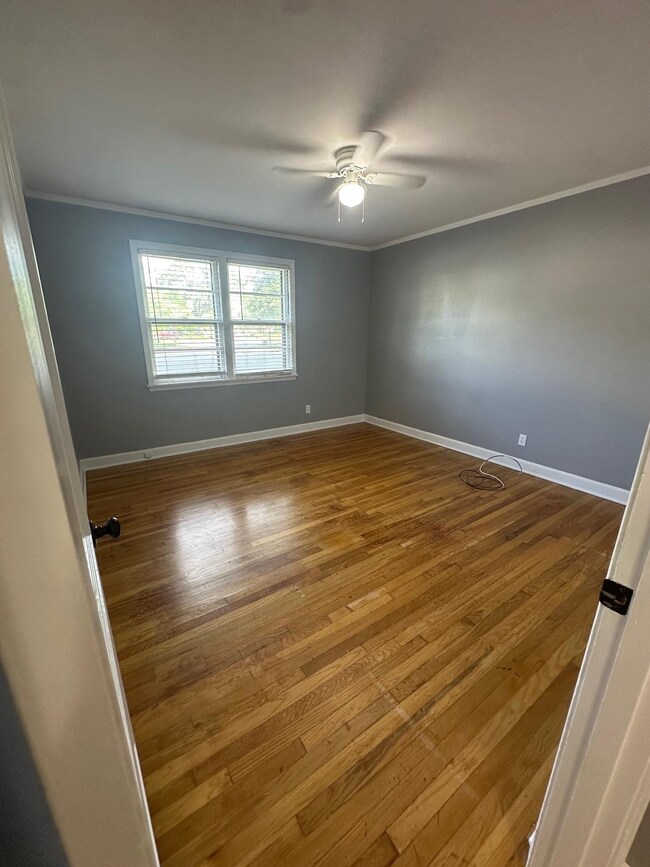 Empty room featuring crown molding, ceiling fan, w