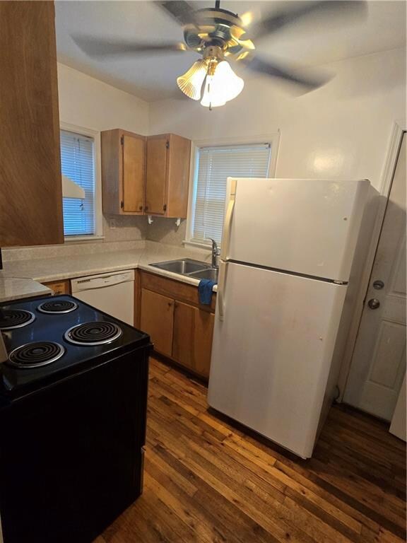 Kitchen featuring dishwashing machine, fridge, stove, a ceiling fan, and dark wood-style flooring