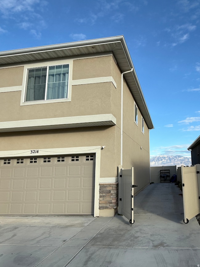 View of home's exterior featuring stucco siding, stone siding, an attached garage, and driveway