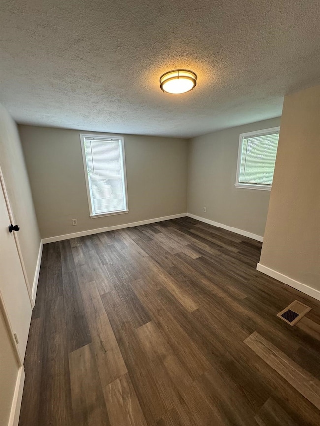 Spare room featuring a textured ceiling and dark wood-style floors
