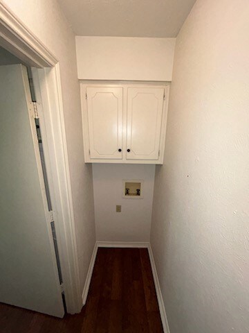 Laundry room with dark wood-style floors, washer hookup, and cabinet space