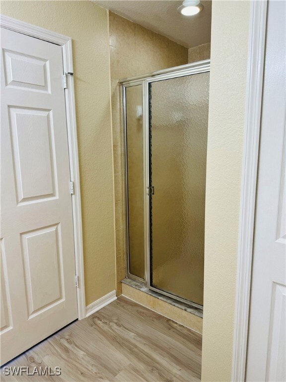 Bathroom with an enclosed shower and wood-type flooring