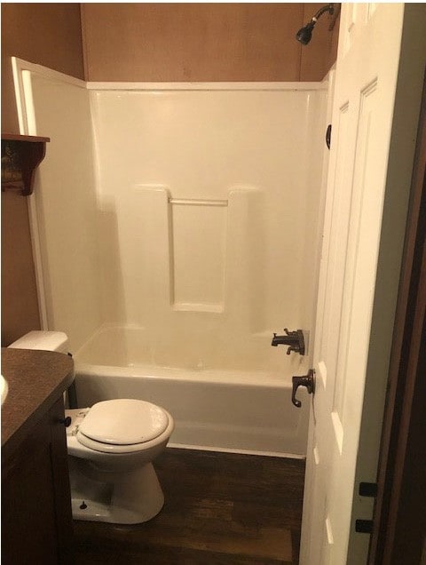 Bathroom with dark wood-style flooring, washtub / shower combination, and vanity