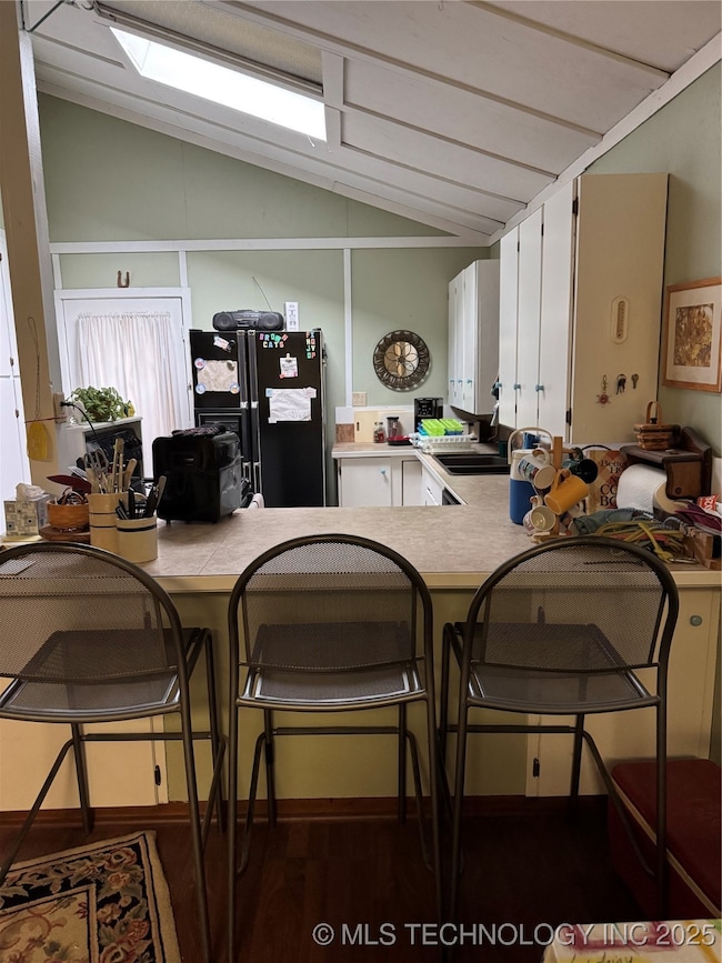 Kitchen featuring refrigerator, lofted ceiling, wo