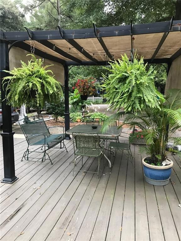 View of patio / terrace featuring a gazebo, a wooden deck, and view of wooded area
