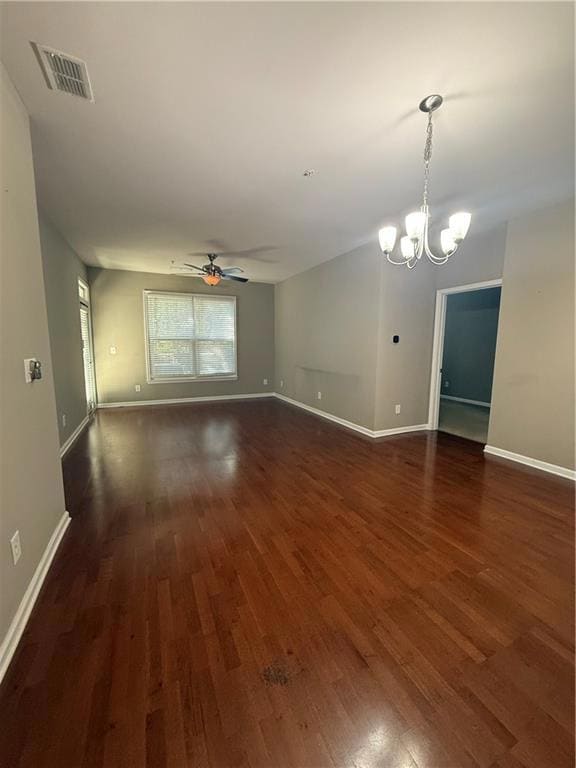 Empty room featuring a chandelier, a ceiling fan, and dark wood finished floors