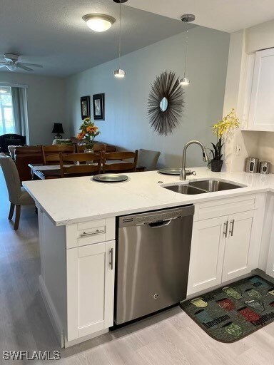 Kitchen featuring pendant lighting, dishwasher, sink, light hardwood / wood-style flooring, and white cabinetry