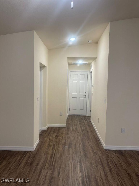 Hall with dark wood finished floors, baseboards, a
