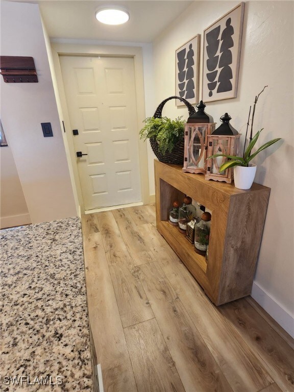 Doorway with light wood-type flooring and baseboar