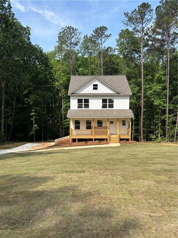View of front of property with roof with shingles, a porch, board and batten siding, and a front lawn