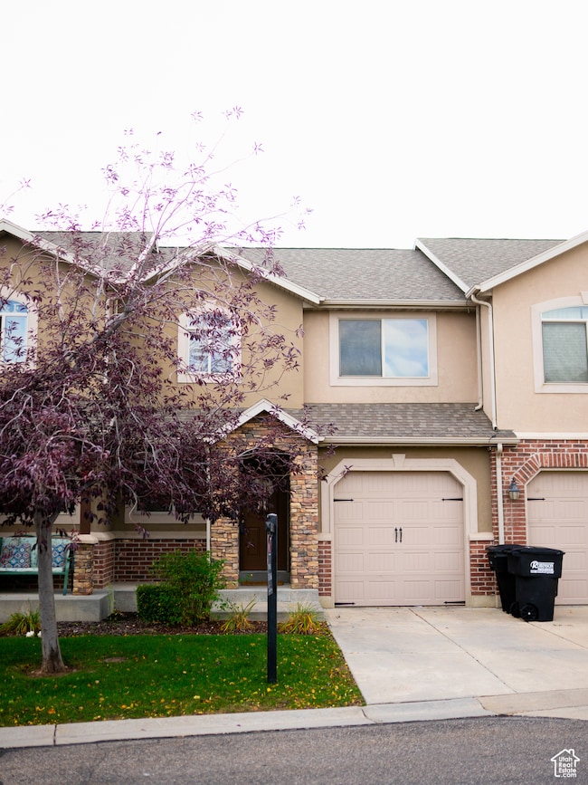 View of front facade featuring driveway, stucco siding, a garage, and a front lawn