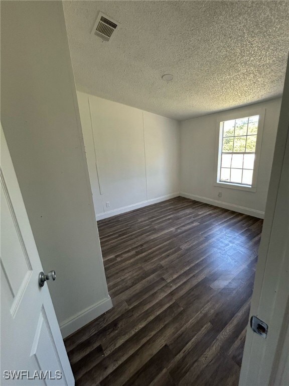 Empty room with baseboards, dark wood finished flo