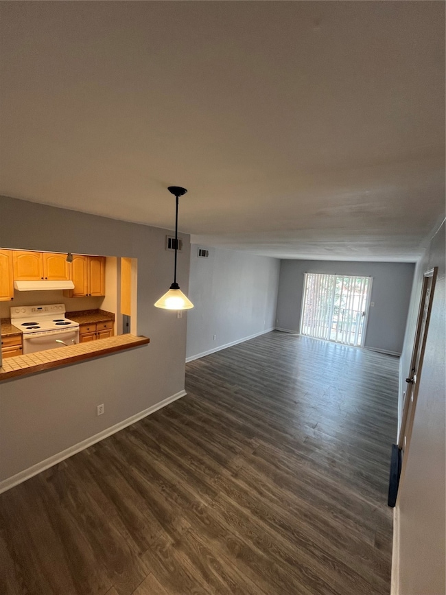 Unfurnished room featuring visible vents, dark wood finished floors, and baseboards