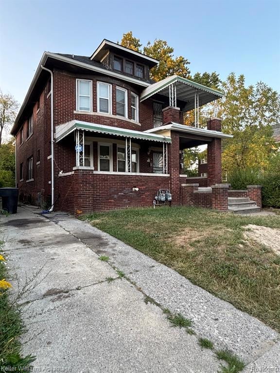 Traditional style home featuring brick siding, a front yard, a porch, and a balcony