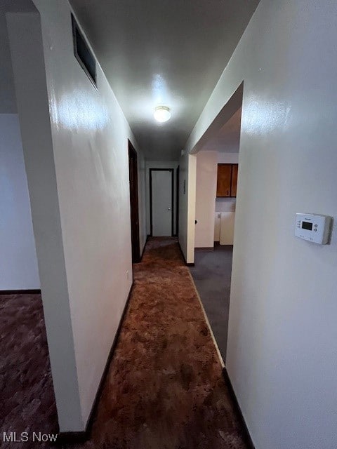 Corridor featuring carpet floors and baseboards