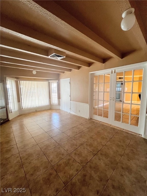 Tiled empty room featuring visible vents, beam cei