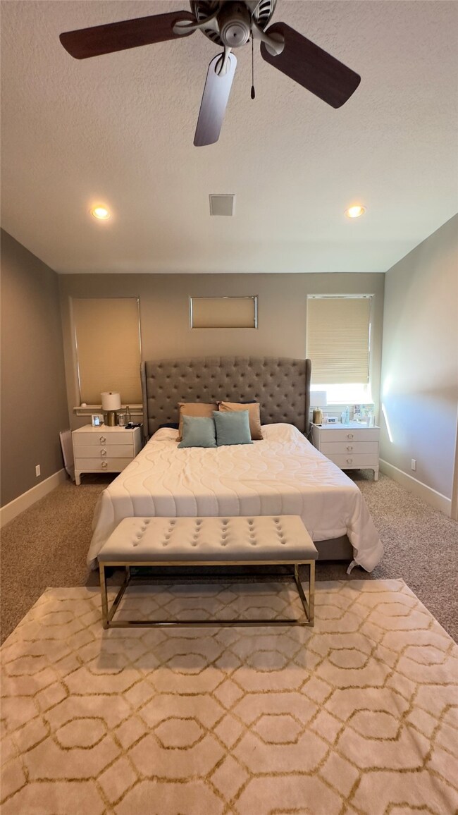 Soft carpeting, large windows, and gentle lighting create a tranquil retreat where modern finishes meet understated elegance in the primary bedroom.
