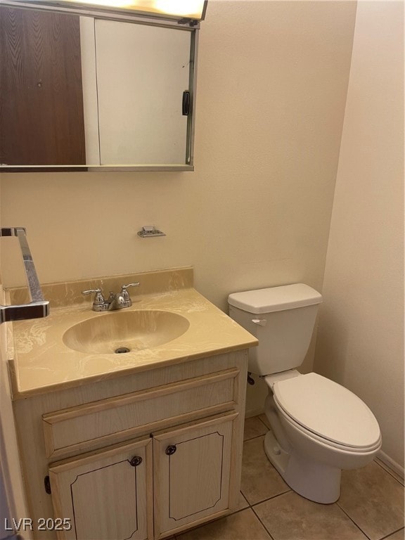Half bath with toilet, tile patterned floors, vani
