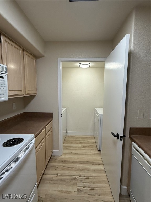 Kitchen with light wood-type flooring, light brown cabinetry, dark countertops, and washing machine and clothes dryer