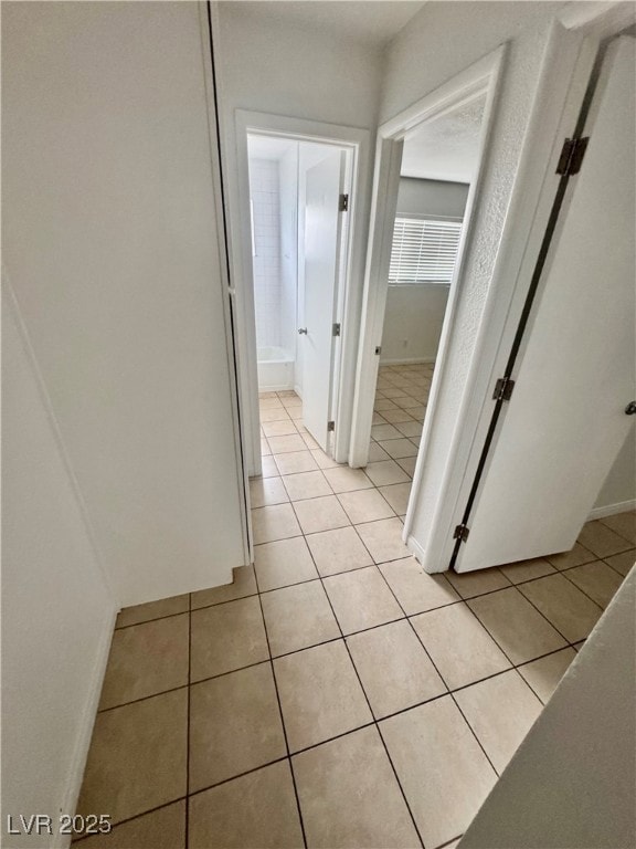 Hallway with light tile patterned flooring and baseboards