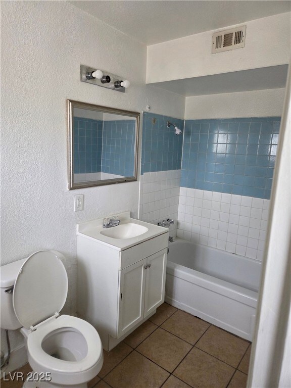 Bathroom featuring toilet, vanity, a textured wall