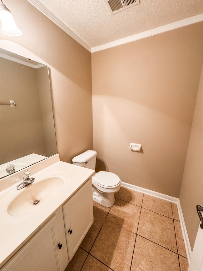 Bathroom with toilet, vanity, tile patterned flooring, a textured ceiling, and ornamental molding