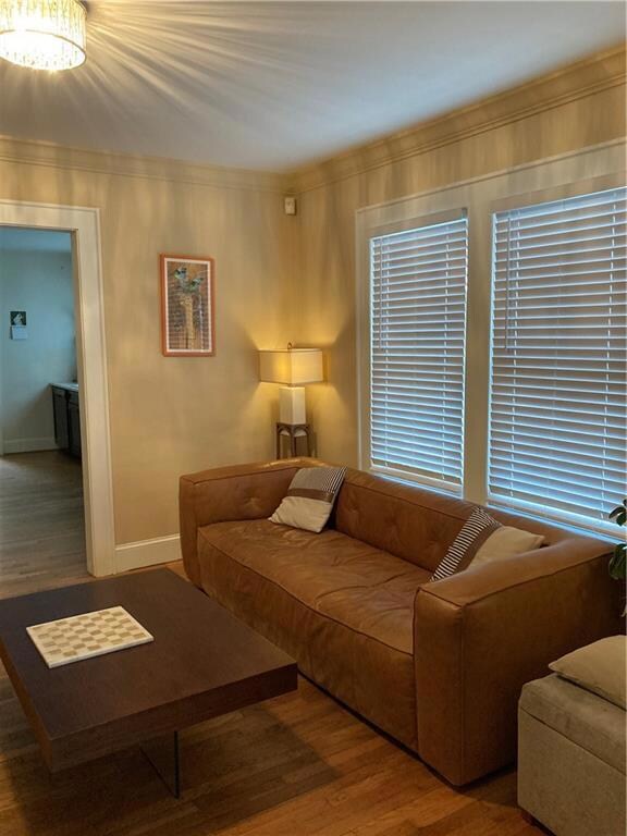 Living room with wood finished floors, crown molding, and a chandelier