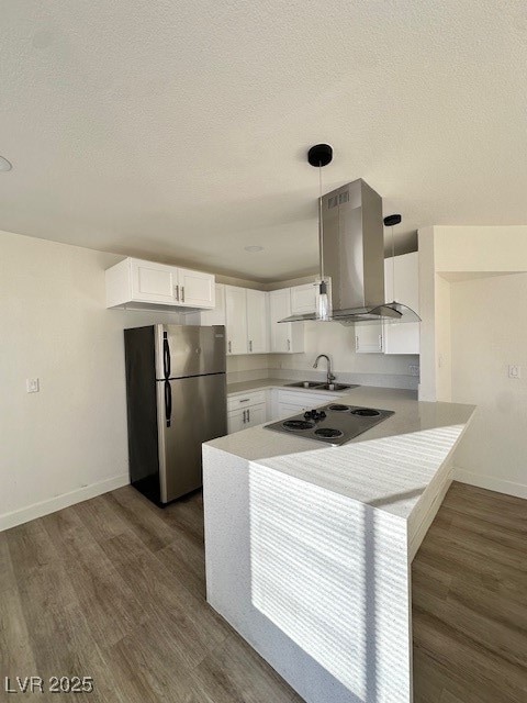 Kitchen featuring decorative light fixtures, white cabinets, fridge, extractor fan, and light countertops