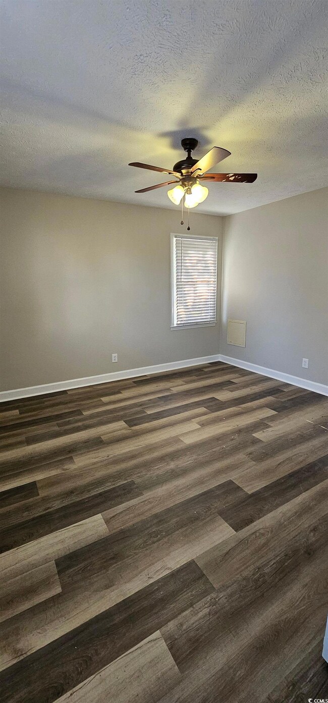Unfurnished room with dark wood-type flooring, ceiling fan, and a textured ceiling
