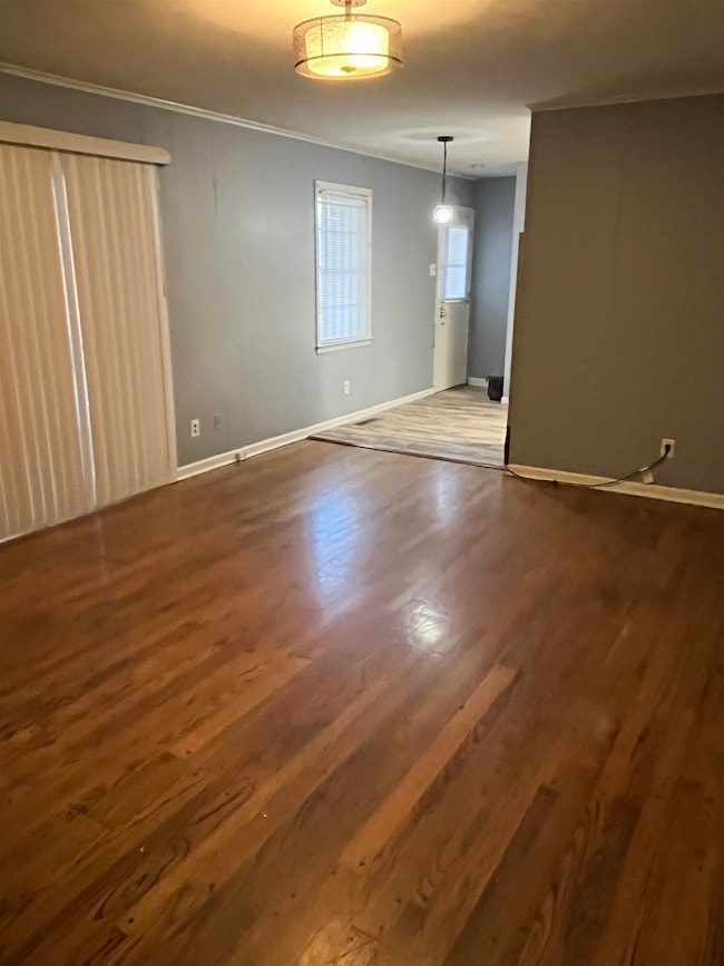 Spare room featuring wood finished floors and crown molding
