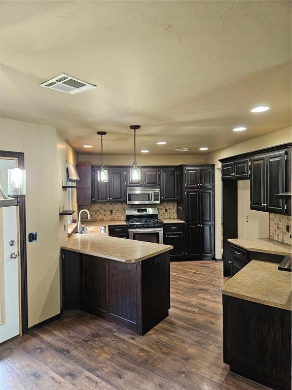 Kitchen with a peninsula, decorative backsplash, range, dark wood finished floors, and light countertops