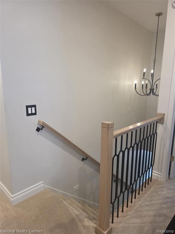 Staircase with carpet and a chandelier