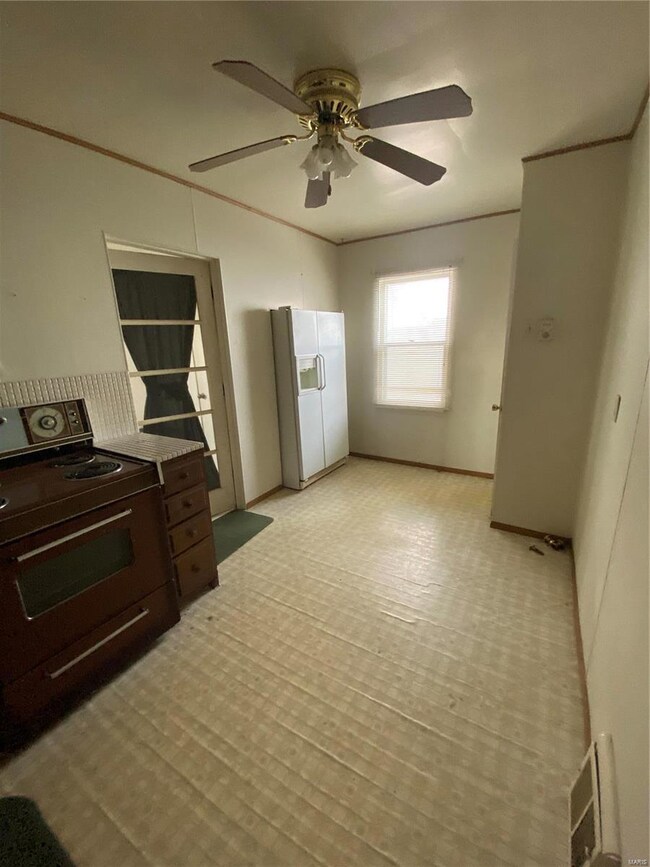 Kitchen with visible vents, ornamental molding, a ceiling fan, freestanding refrigerator, and range