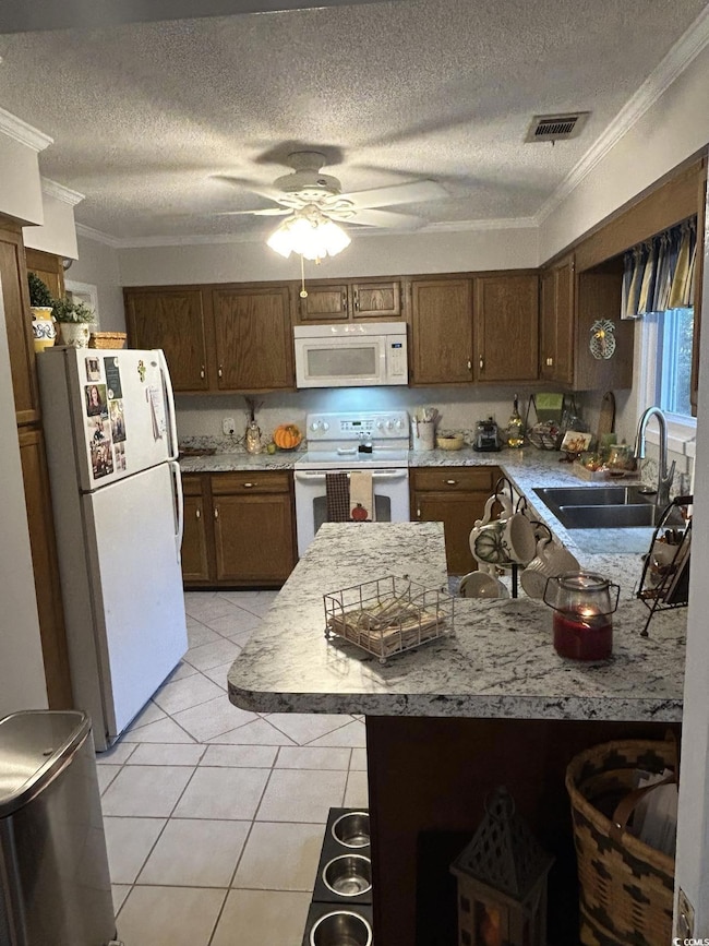 Kitchen with white appliances, ornamental molding, ceiling fan, a textured ceiling, and light tile patterned floors