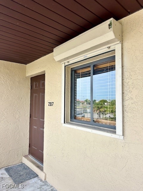 Doorway to property featuring covered porch & hurricane shutters!