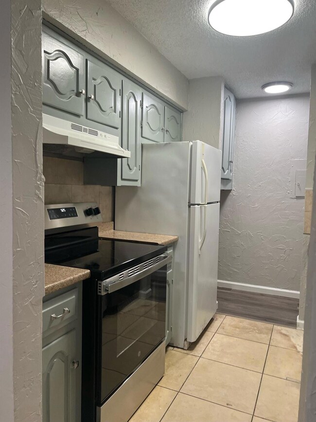 Kitchen featuring range hood, range, a textured ce
