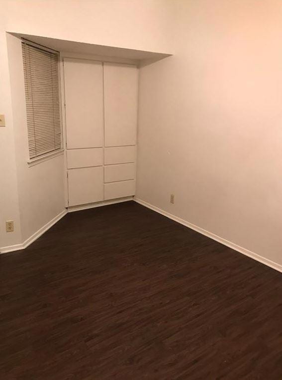 Empty room with baseboards and dark wood finished