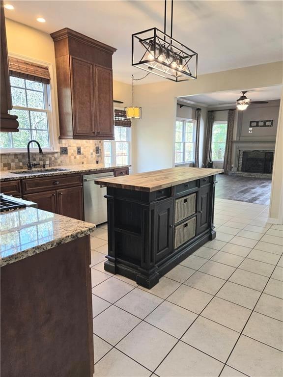 Kitchen featuring wood counters, light tile patterned floors, a fireplace, backsplash, and dark brown cabinets