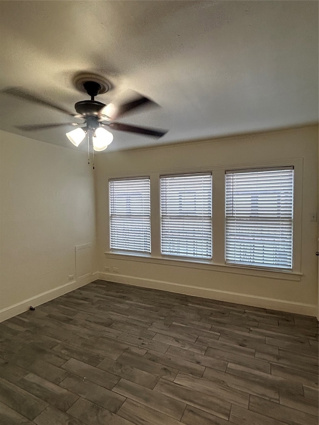 Spare room featuring dark wood finished floors, a textured ceiling, and a ceiling fan