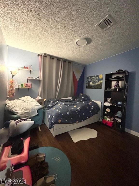 Bedroom featuring a textured ceiling and wood fini
