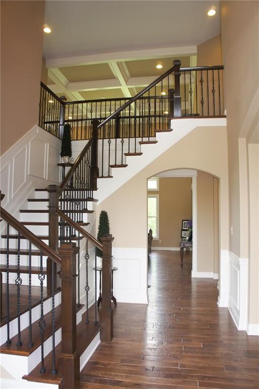 Studding two story entry with wrought iron banister and wood flooring on the stairs. 