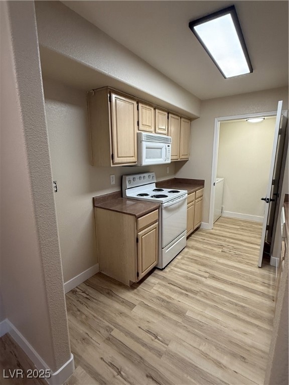 Kitchen featuring light wood-type flooring, electric range, baseboards, and dark countertops