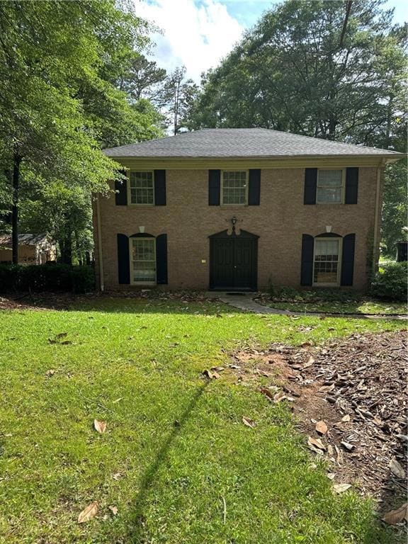 Colonial home with a front lawn and brick siding